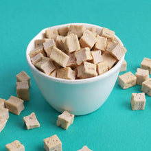 White bowl filled with beige square-shaped cookies on a teal background