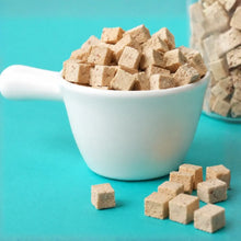 Brown sugar cubes in a white bowl on a turquoise background