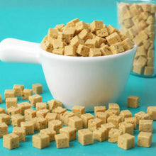 Cubes of tofu in a white bowl on a turquoise background