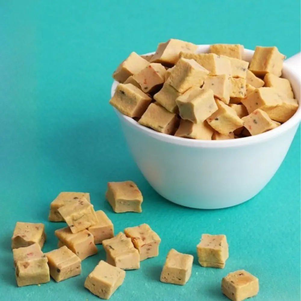 Dog treats in a white bowl on a teal background