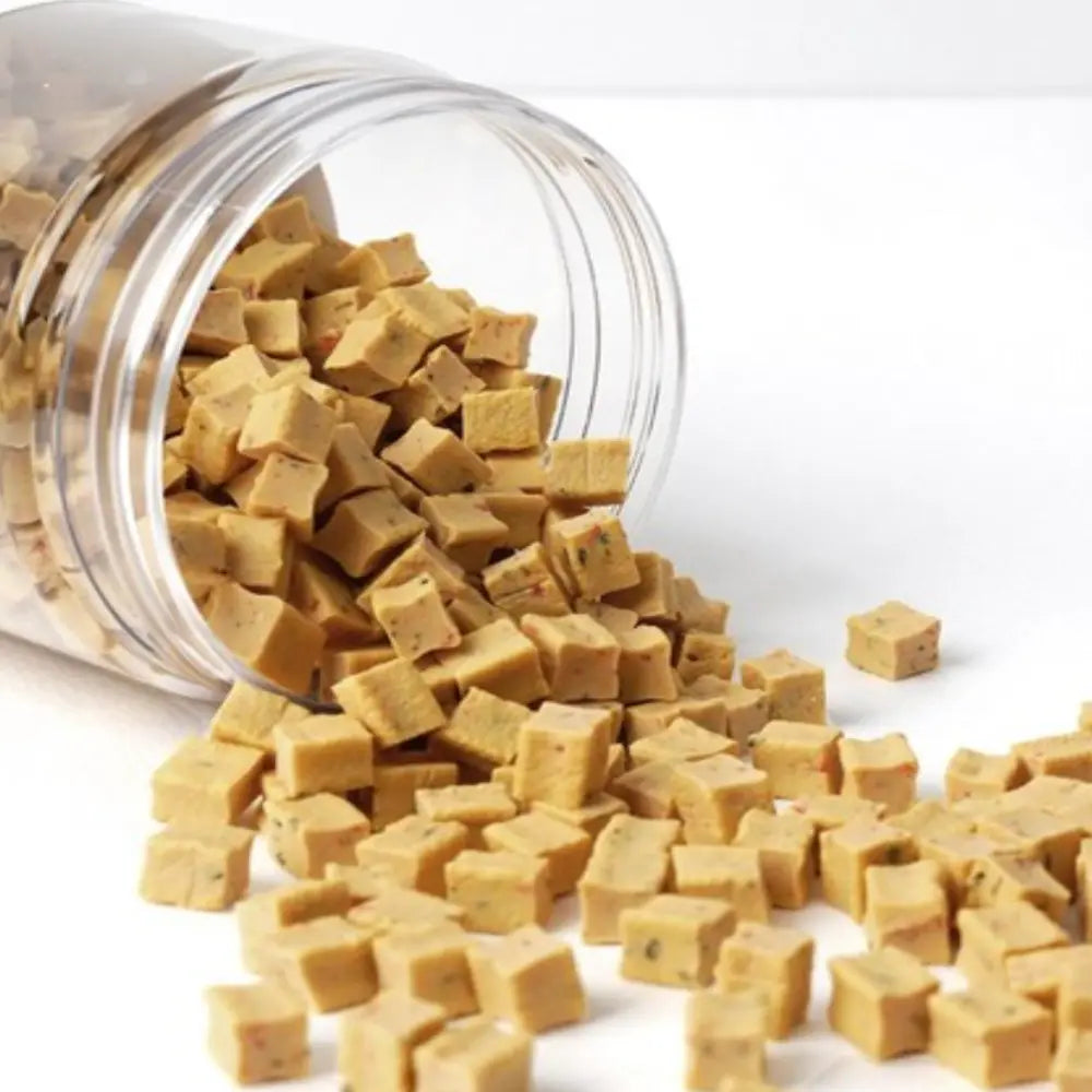 Clear jar of square-shaped brown dog treats on a white background