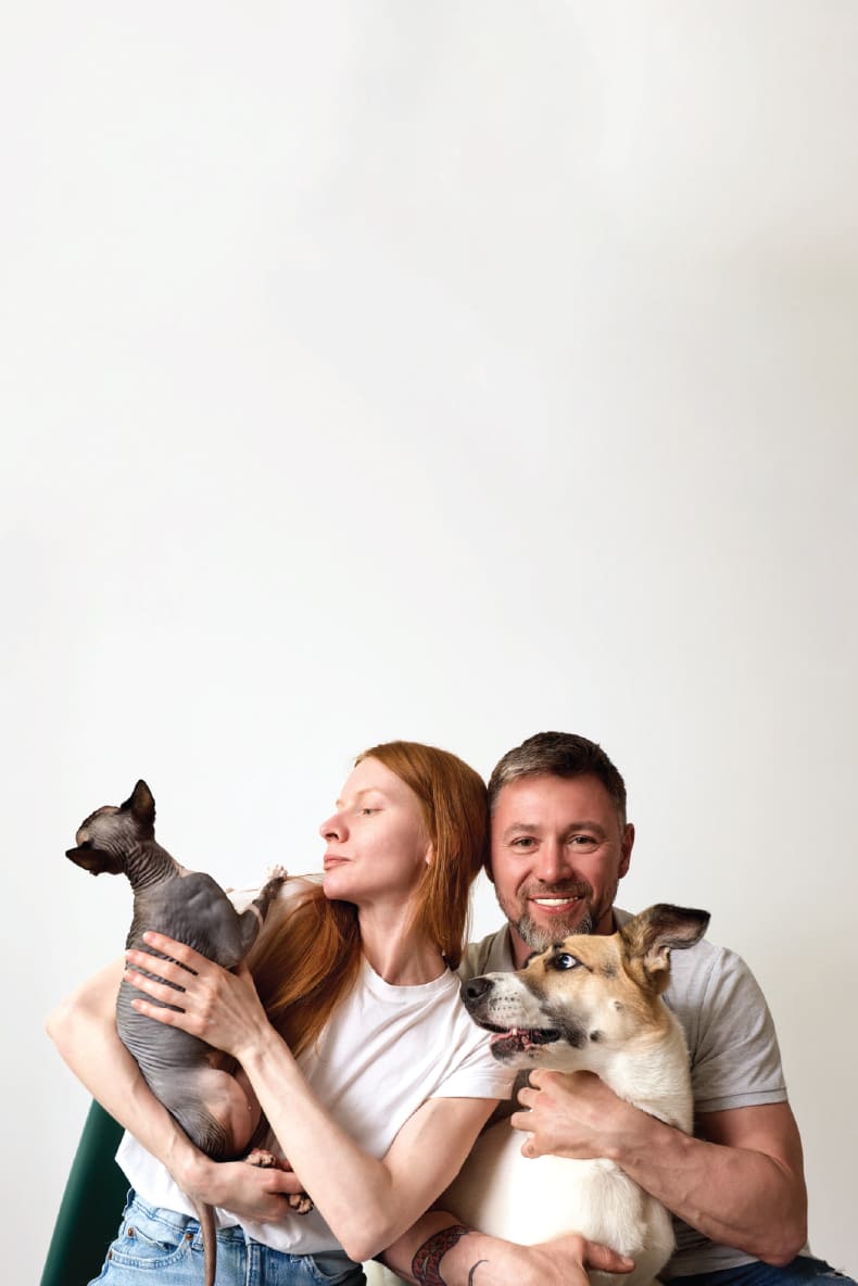 Man and woman holding two dogs against a white background