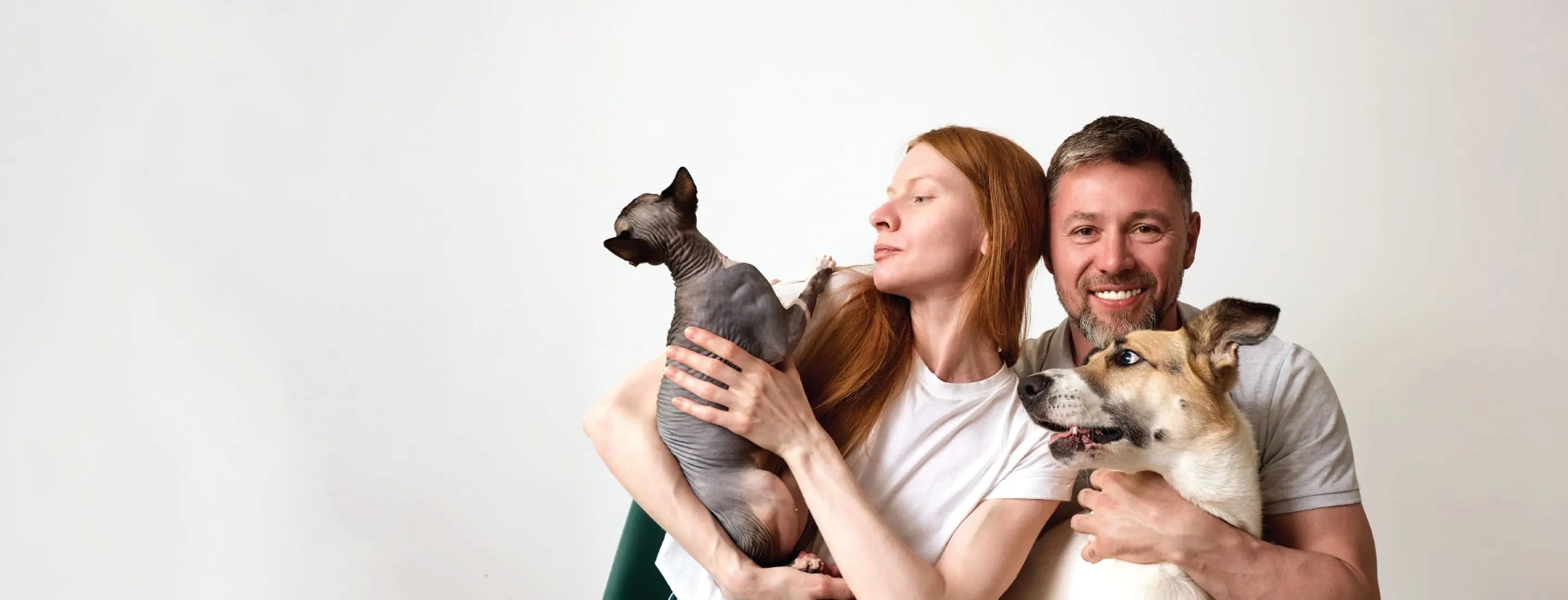 Man and woman holding two dogs against a white background